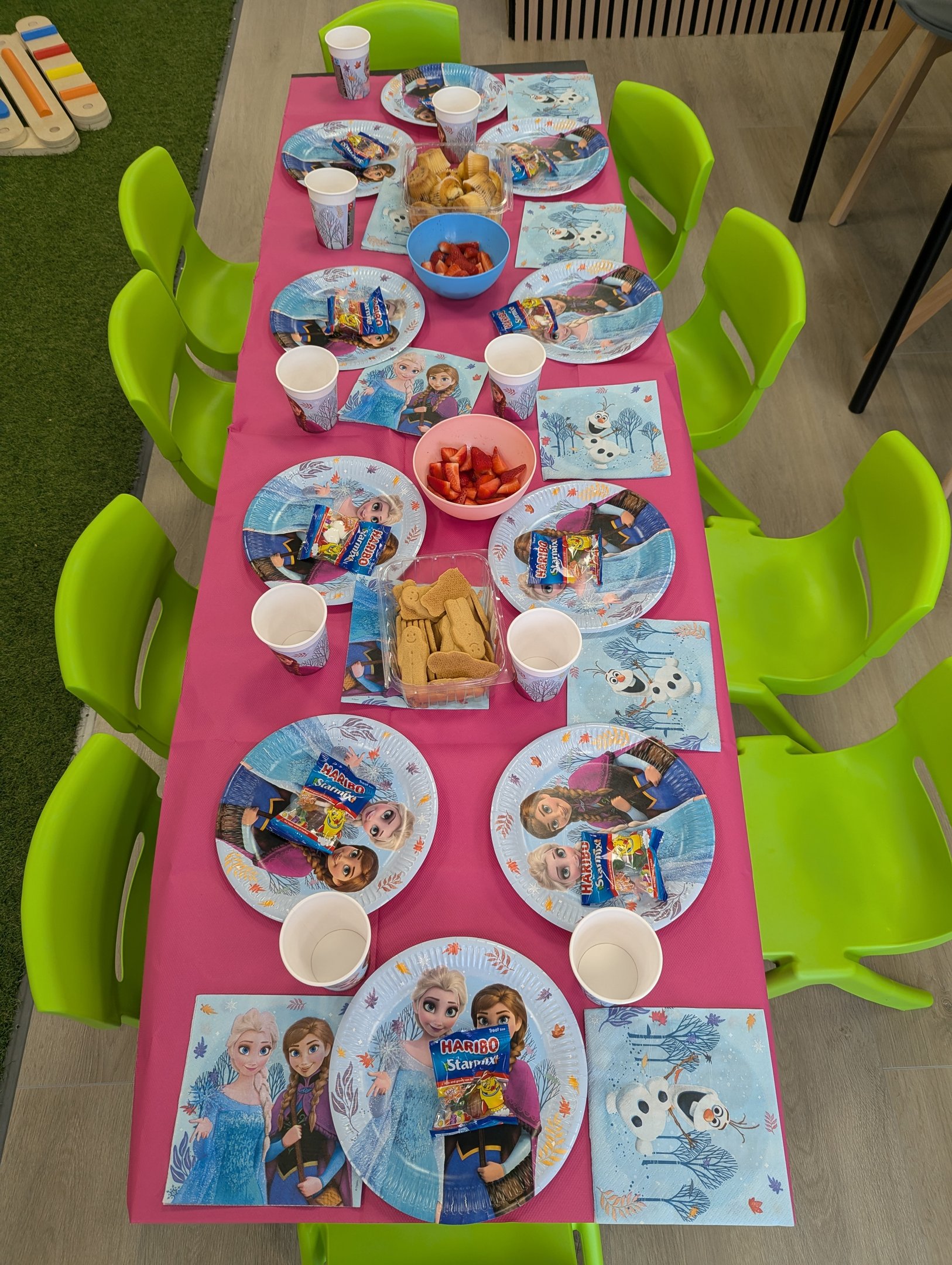 A party table laid out with plates, cups and treats